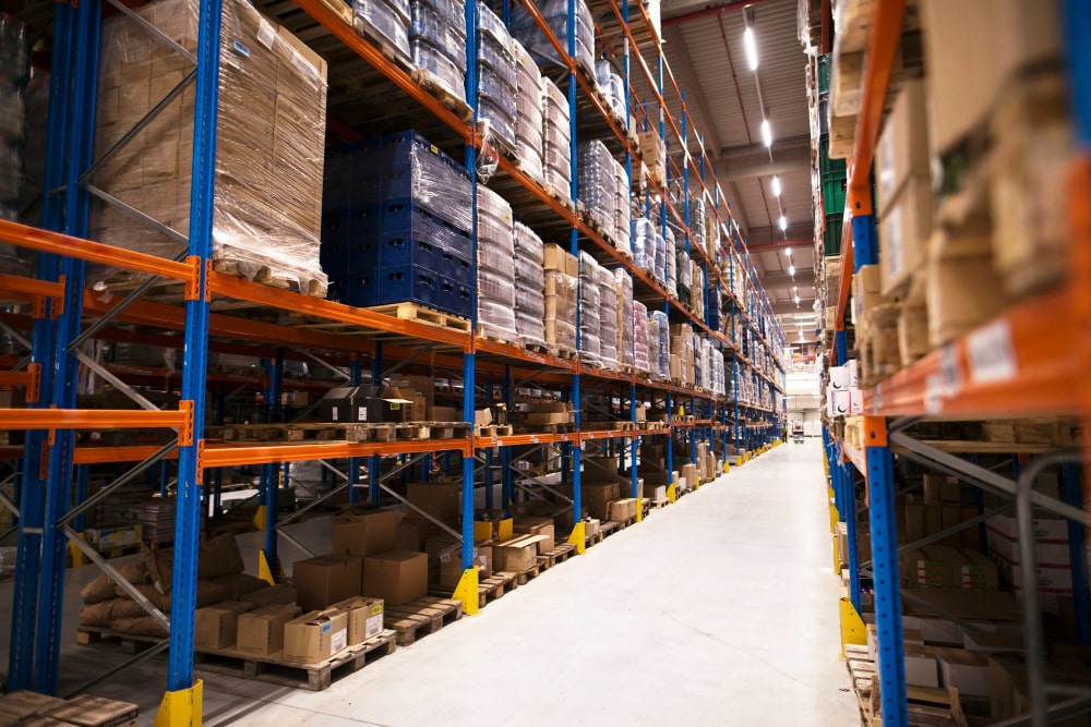 interior large distribution warehouse with shelves stacked with palettes goods ready market min